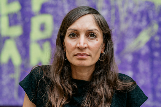 Es ist das Portraitfoto zu sehen von Gilda Sahebi. Die Aufnahme ist draußen im grünen Hintergrund.