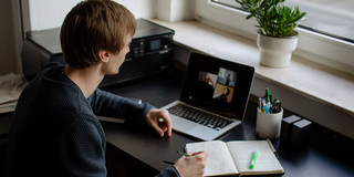Lernen mit verschiedenen Medien Ein Student arbeitet mit Laptop und Notizbuch.